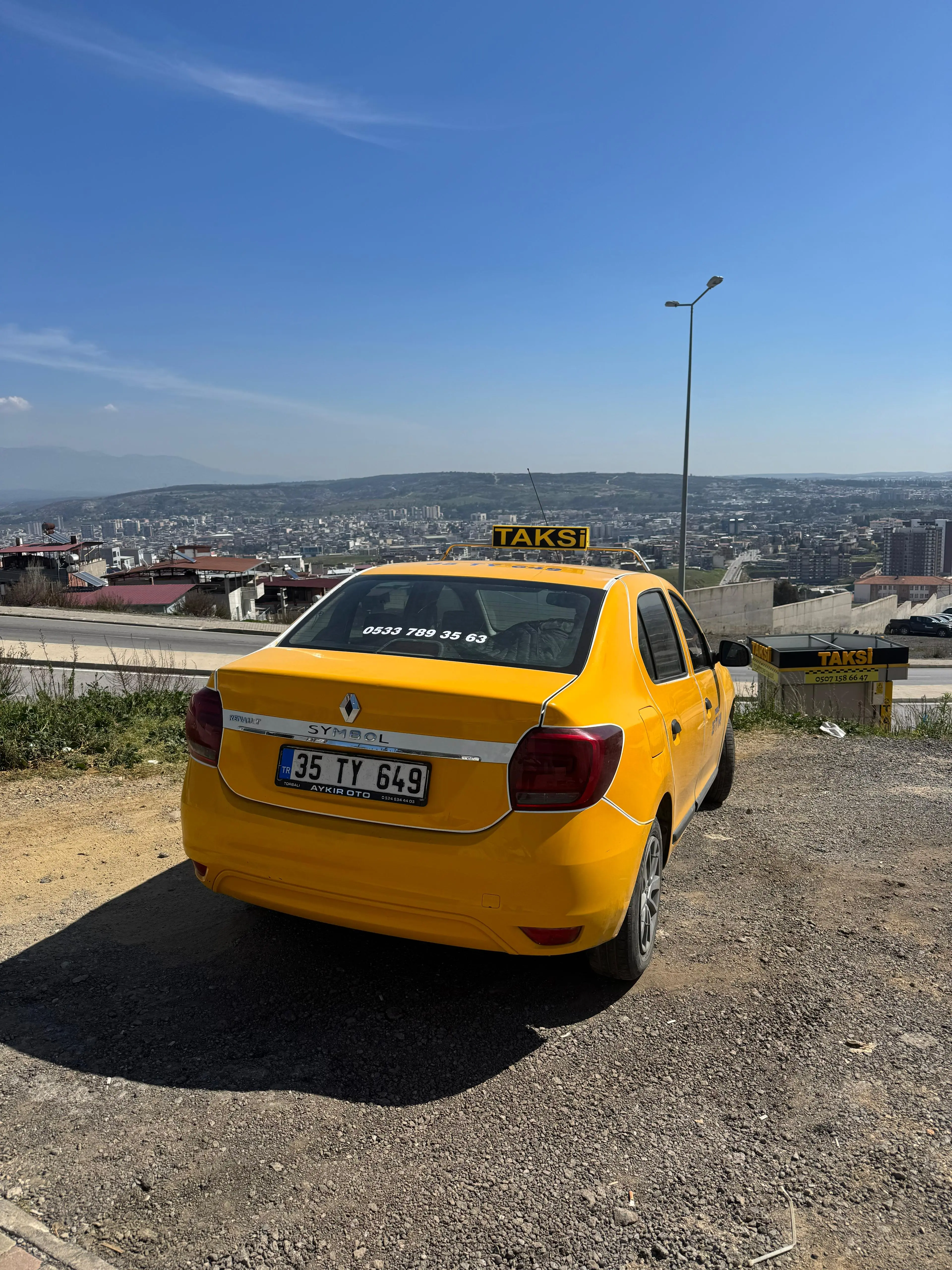 Torbalı şehir manzarasında 35 TY 649 plakalı sarı taksi